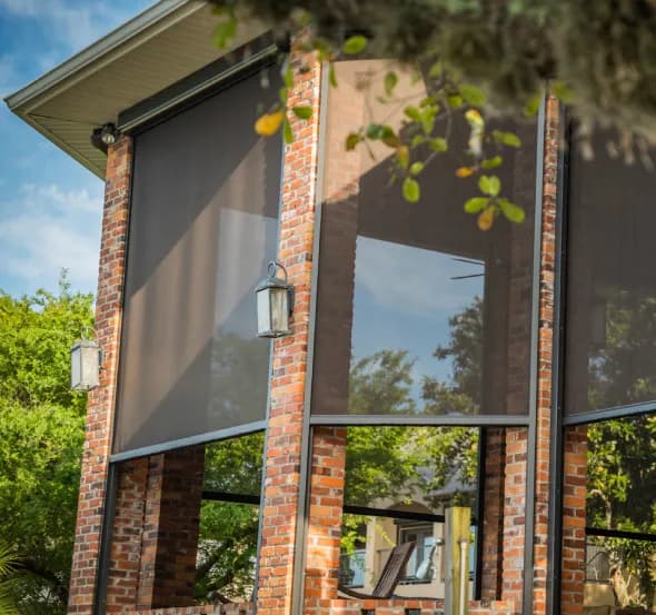 SunPro motorized screens partially lowered across a brick porch opening, filtering daylight.