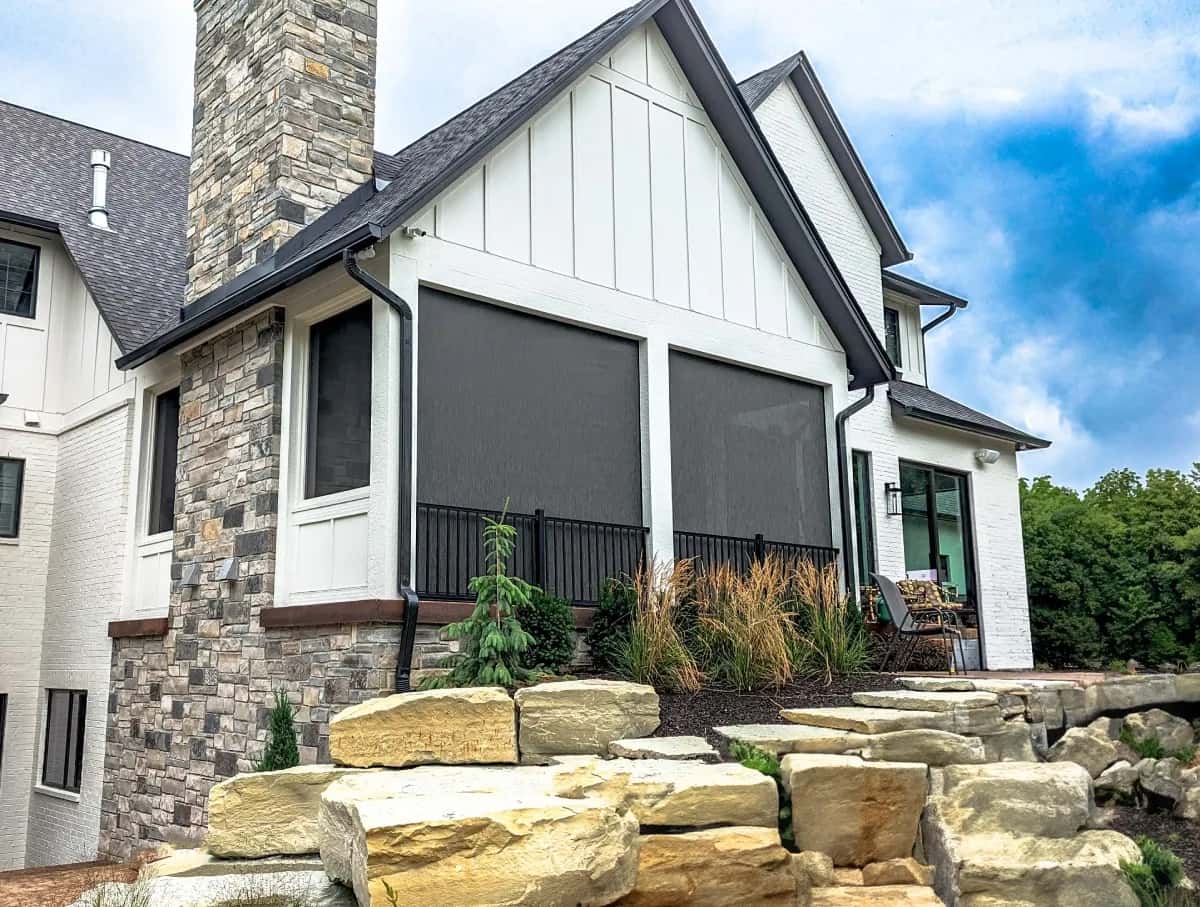 SunPro motorized screens installed on the rear porch of a two-story home, viewed from the garden.
